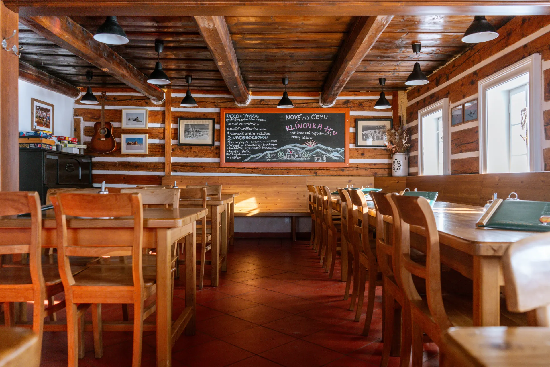 Útulný interiér restaurace s dřevěnými trámy a kamny